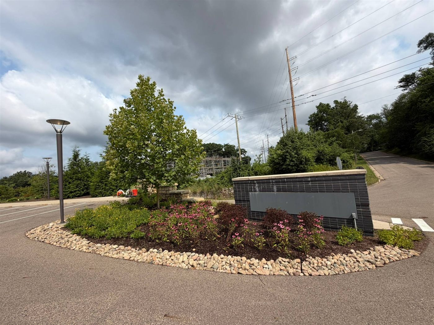 Commercial landscape planting bed with river rock edging and a new tree at a business entrance