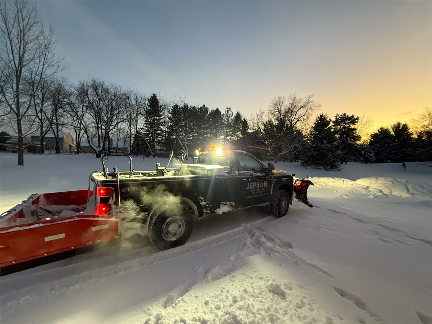 Jepson Landscaping plow truck and trailer clearing snow at sunrise
