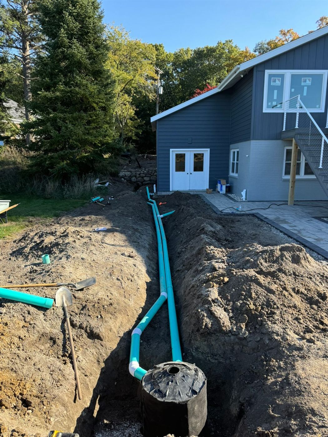 Stormwater drainage pipes and catch basin in the trench beside the new patio