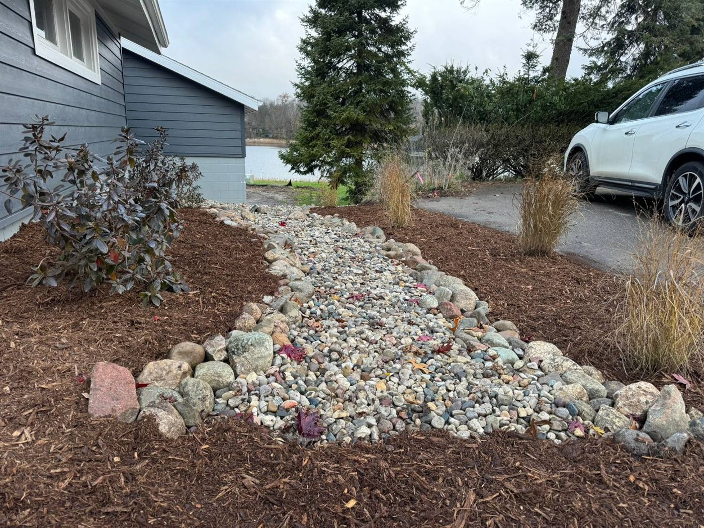 Dry creek bed with river rock and boulder edging leading toward the lake