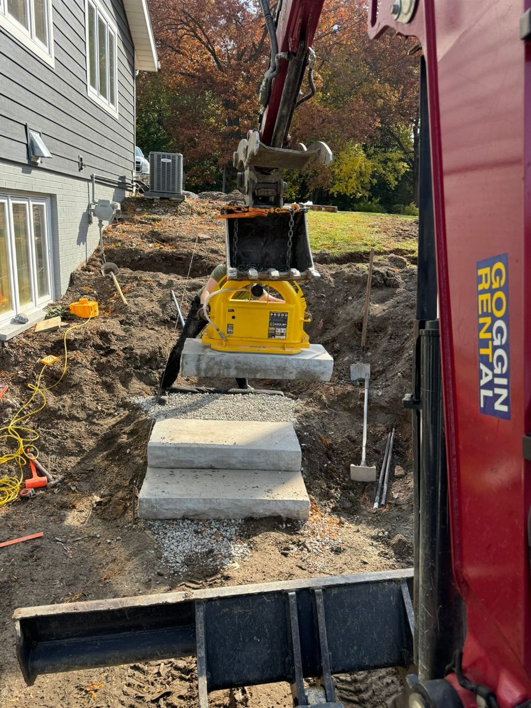 Crew setting stone steps with an excavator and vacuum lifter