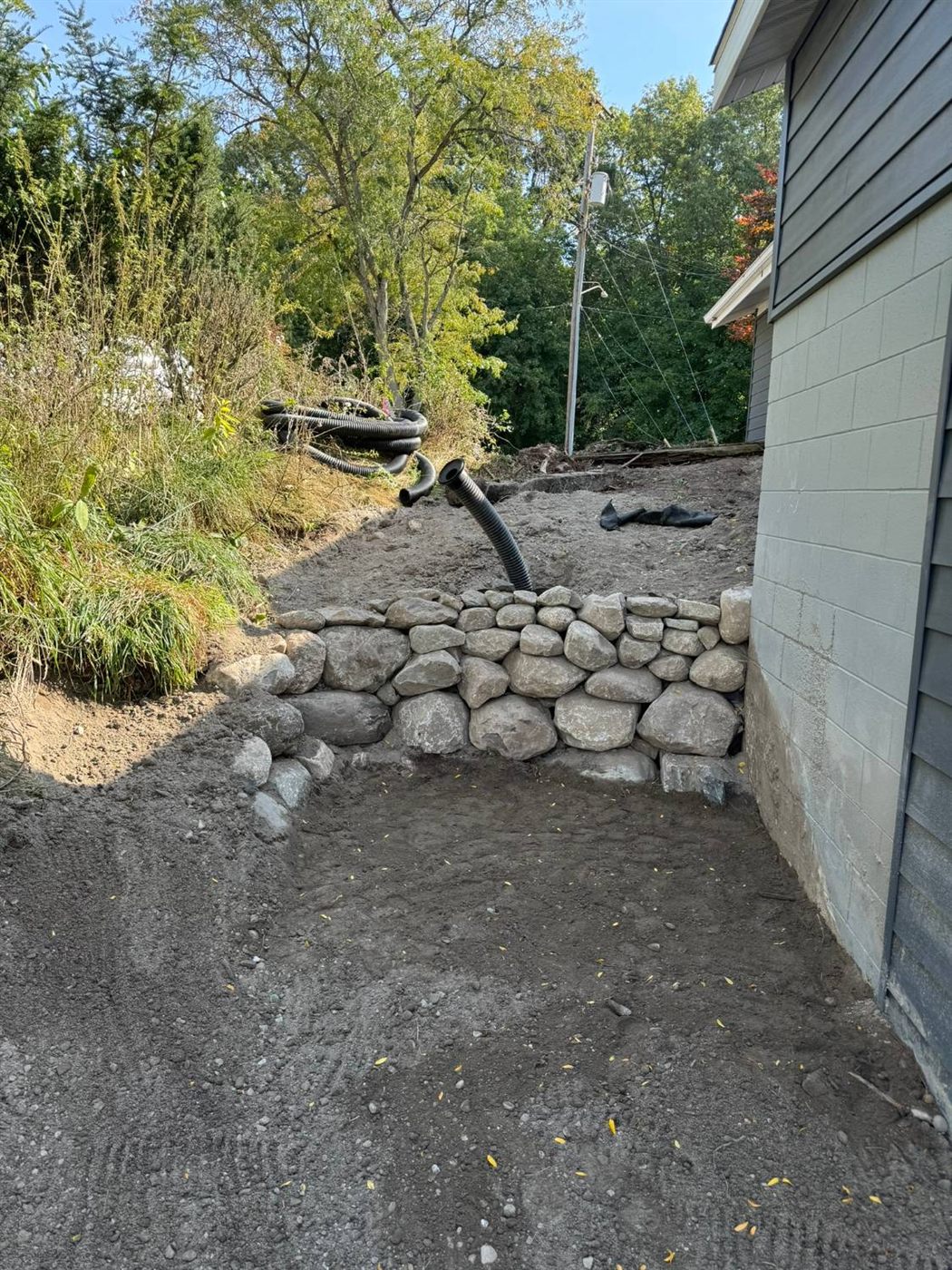 Boulder retaining wall with a drain pipe during construction