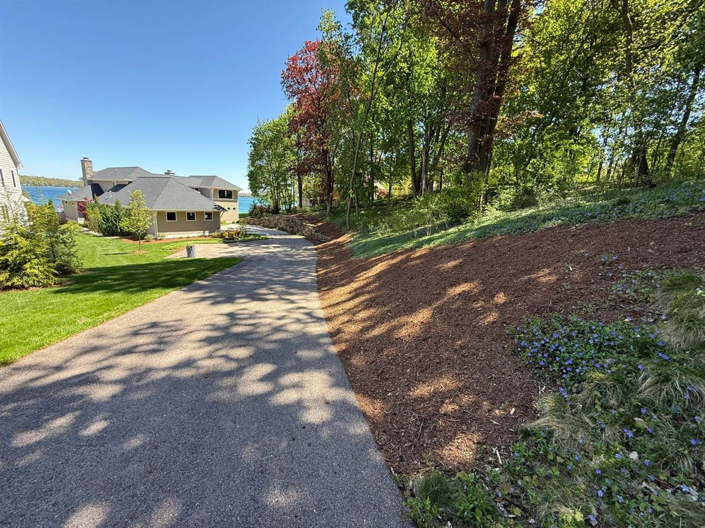 Freshly mulched hillside bed along a driveway and stone retaining wall
