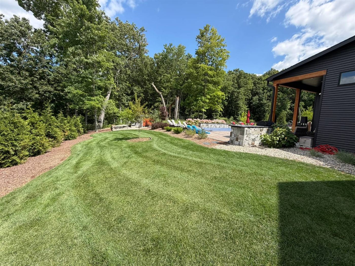 Rolling side lawn with curved mulch beds leading to the pool area