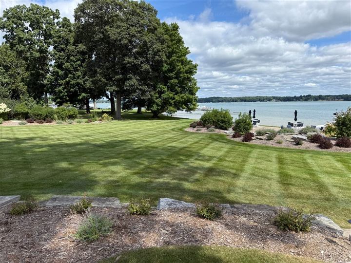 Large striped lakefront lawn with planting beds and stone edging