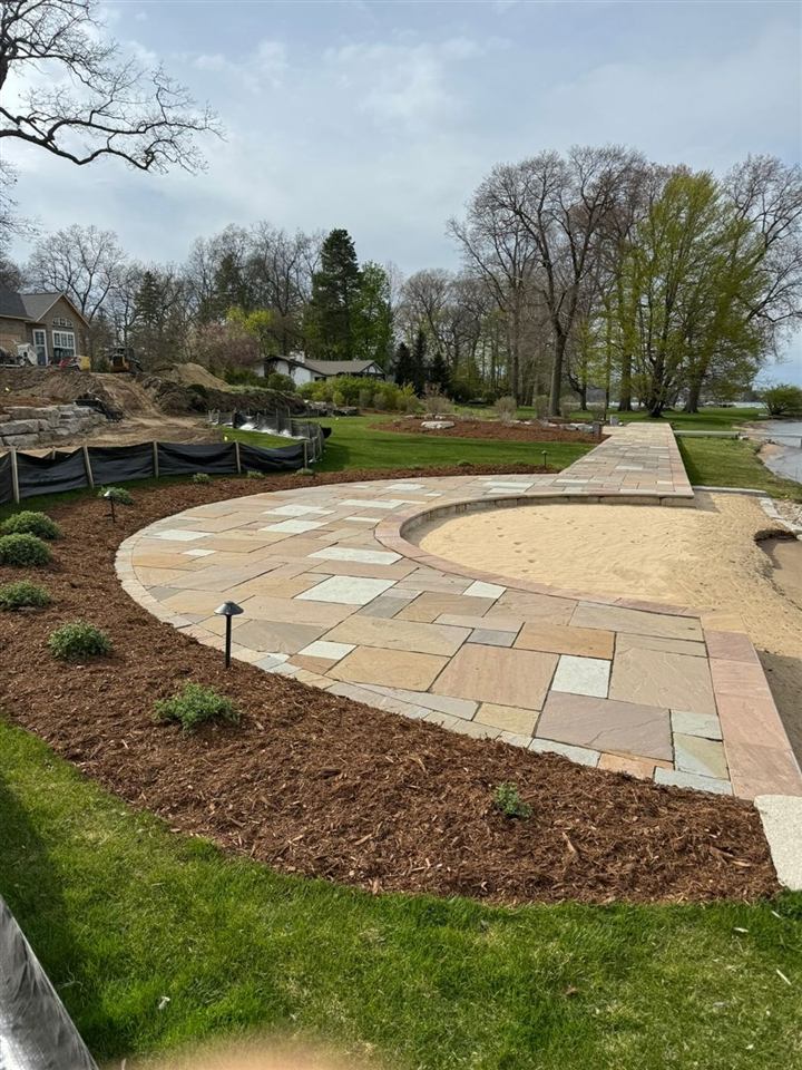 Curved flagstone patio with fresh mulched beds and landscape lighting